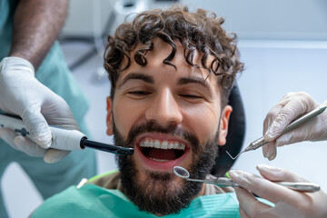 Male dentist performing orthodontic checkup on patient in modern dental clinic
