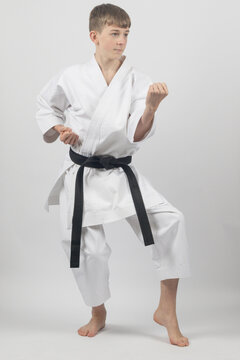 Fifteen year old male teenage karate black belt in a cat stance Blocking, studio shot against a white background