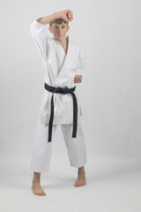 Fifteen year old male teenage karate black bel in sanchin stance doing a head block, studio shot against a white background