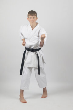 Fifteen year old male teenage karate black bel in sanchin stance doing a body block , studio shot against a white background