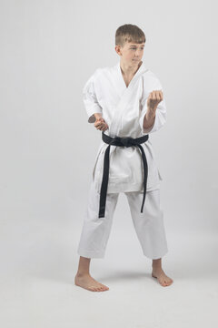 Fifteen year old male teenage karate black bel in sanchin stance doing a body block , studio shot against a white background