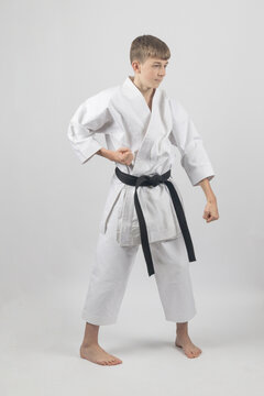 Fifteen year old male teenage karate black bel in sanchin stance doing a groin block, studio shot against a white background