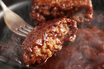 鉄板の上で焼く熱々の湯気の上がるジューシーなハンバーグステーキ