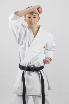 Fifteen year old male teenage karate black belt performing a head block, studio shot against a white background