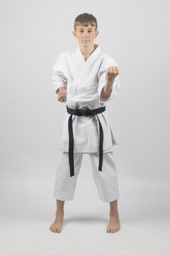 Fifteen year old male teenage karate black belt body block, studio shot against a white background