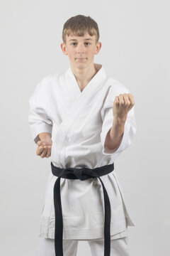 Fifteen year old male teenage karate black belt body block, studio shot against a white background