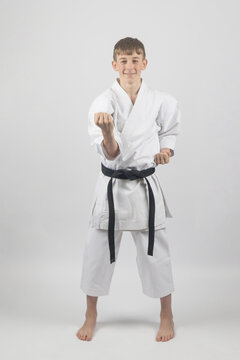 Fifteen year old male teenage karate black belt body block, studio shot against a white background