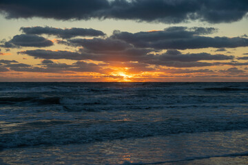 Evening landscape of sea water waves crushing on sandy beach at sunset