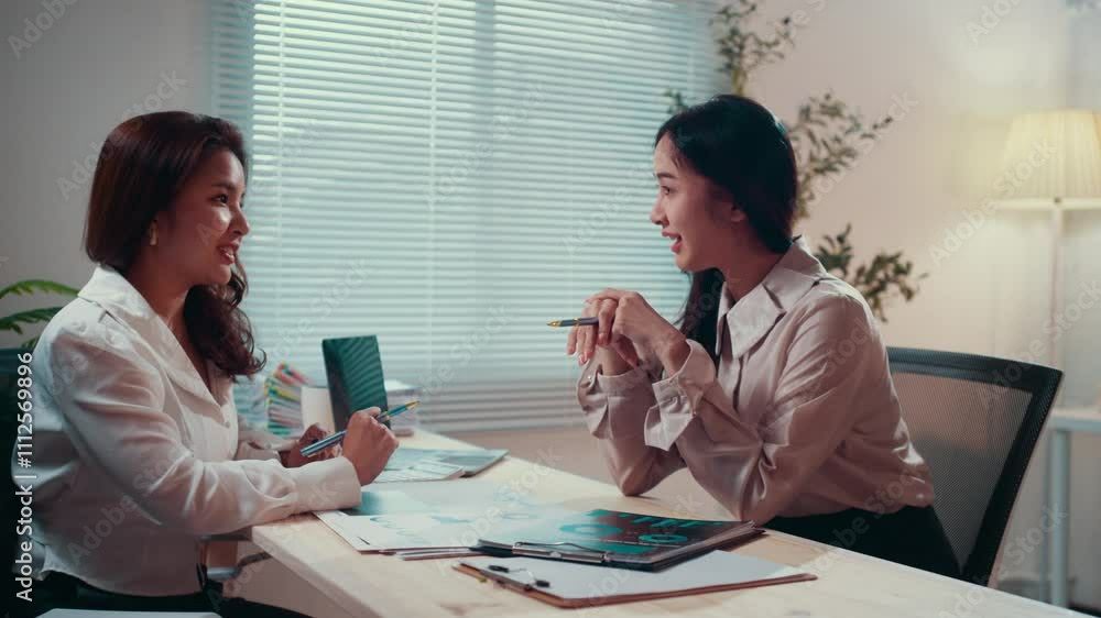Fototapete two businesswomen engage in a conversation at a desk in an office. one gestures with a pen, emphasiz