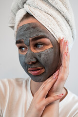 portrait of young woman  getting facial care clay or mud mask isolated on white