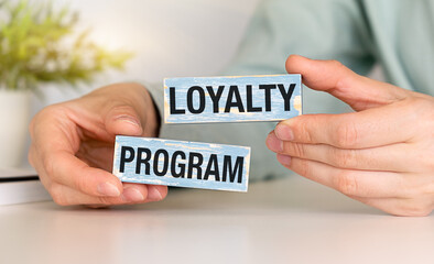 Loyalty program text on wooden blocks and on gray table with hands.