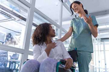 Obraz premium Dark-haired nurse carrying a wheelchair with a female patient