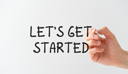 The hand of a business woman with a pen in her hands writes on a transparent background Let's Get Started, Business Concept.