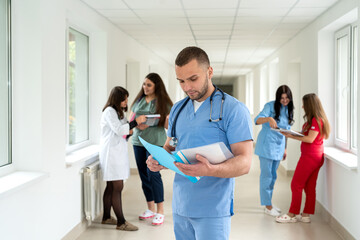 Obraz premium Group of positive caucasian doctors wearing uniform and stethoscope in college hallway