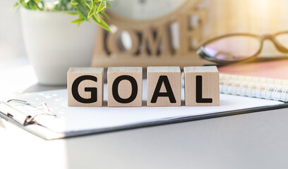 Goal text on wooden cubes with table lamp background. Goal setting and business concept.