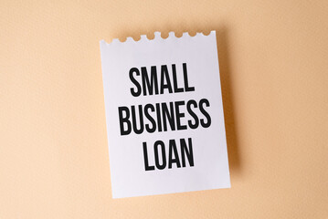 Small Business Loan text on white sticky note on yellow background.