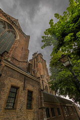 A majestic Gothic church under a dramatic cloudy sky. The intricate brickwork, towering windows,...