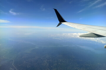 View through airplane window of commercial jet plane wing flying high in the sky. Air travelling...