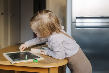 Portrait of toddler girl playing with toys in playroom. Adorable two years old girl at home, enjoying creative playtime in a bright, cozy environment. Generation alpha concept. Part of a series