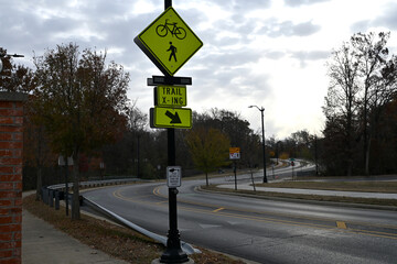 Yellow bicycle and pedestrian crossing sign on a pole in front of a curved street