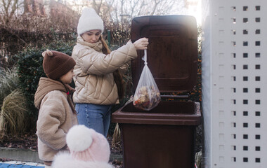 Generation Alpha and Zero waste. Mom with daughters throws household garbage into trash cans....
