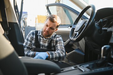 Car detailing and car care concept - Professional using steam vacuum for draining stains
