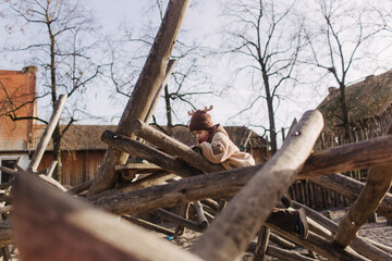 Cute girl, preschooler female kid playing, sliding in kid wooden playground, concept image for child development, healthy kid playing outside. Gen Alpha. Part of a series