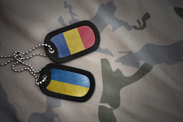 vintage army blank, dog tag with flag of romania and ukraine on the khaki texture background....