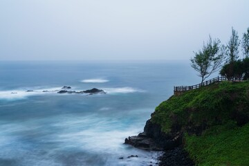 Obraz premium Serene coastal view with rocky cliffs and calm ocean.