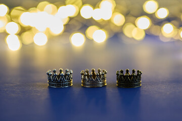 three shiny crowns and a lights on blue background. Epiphany and three kings day holiday...