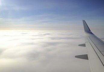Fototapeta premium Aerial View of Airplane Wing Above Soft White Clouds with a Beautiful Blue Sky in the Background Capturing the Essence of Travel and Exploration