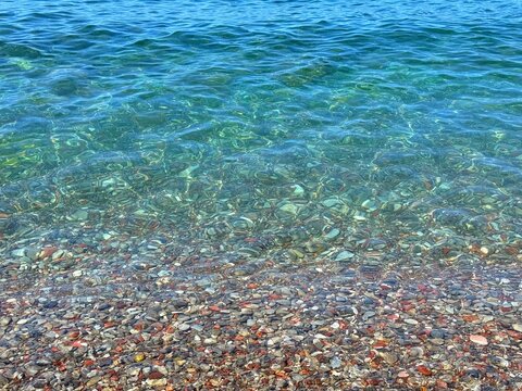 Sea blue clear water with smooth pebbles at the bottom.