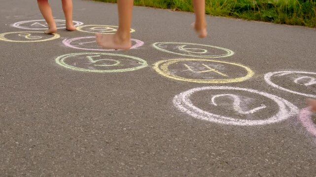 Children jumping hopscotch on asphalt. Selective focus.