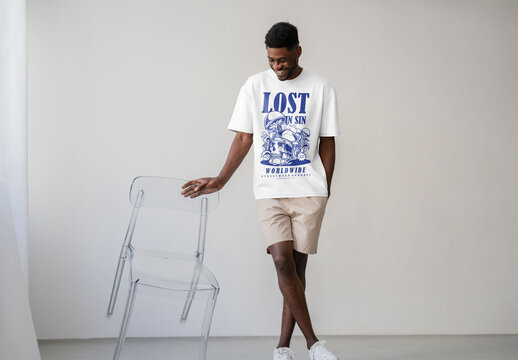 Mockup Of Man Wearing Customizable T-Shirt Leaning On Chair
