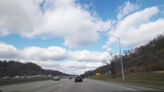 Car automobile driver point of view pov moving towards and through multi-lane roadway, highway, and Pennsylvania interstate outside Pittsburgh, PA during traffic and cars driving in fall weather