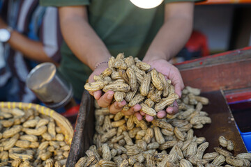 A trader is holding boiled peanuts that are still warm and ready to eat