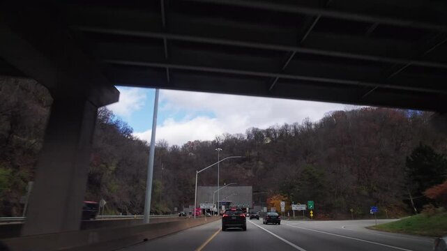 Car automobile driver point of view pov moving towards and through multi-lane roadway, highway, and Pennsylvania interstate outside Pittsburgh, PA during traffic and cars driving in fall weather