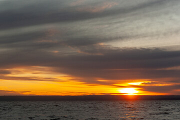 Obraz premium a sunset over a body of water with a few waves.