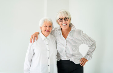Portrait of two elderly woman over grey background.
