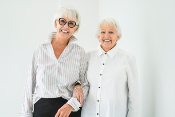 Portrait of two elderly woman over grey background.
