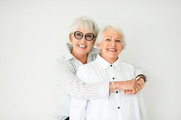 Portrait of two elderly woman over grey background.