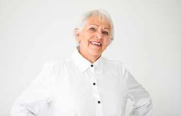 Portrait of elderly woman in eyeglasses over grey background.