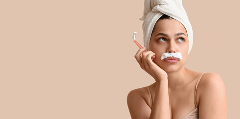 Beautiful young thoughtful woman with razor and shaving foam on beige background. Depilation concept