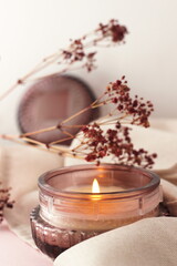 burning candle in a glass jar placed on a textile background