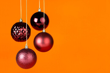 Four burgundy color Christmas balls hanging on gold strings