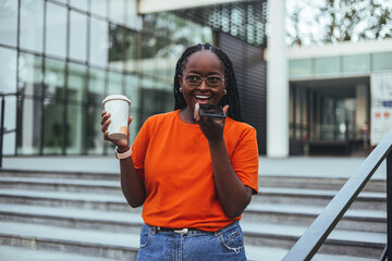 Joyful Woman Enjoying Coffee Break While Chatting on Smartphone Outdoors