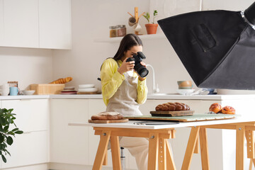 Young female photographer taking picture of food in modern kitchen