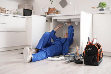 Mature female plumber installing sink in kitchen