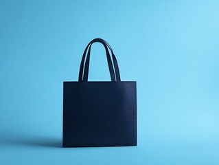A minimalistic and chic navy blue tote bag styled on a powder blue solid background