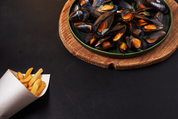 Delicious mussels served with crispy fries on wooden platter, horizontal